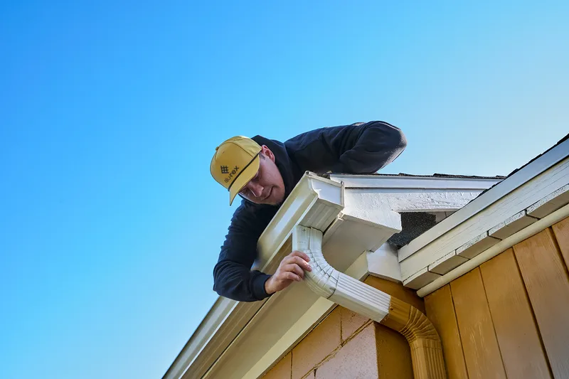 Installer adjusting a downspout elbow during a gutter repair